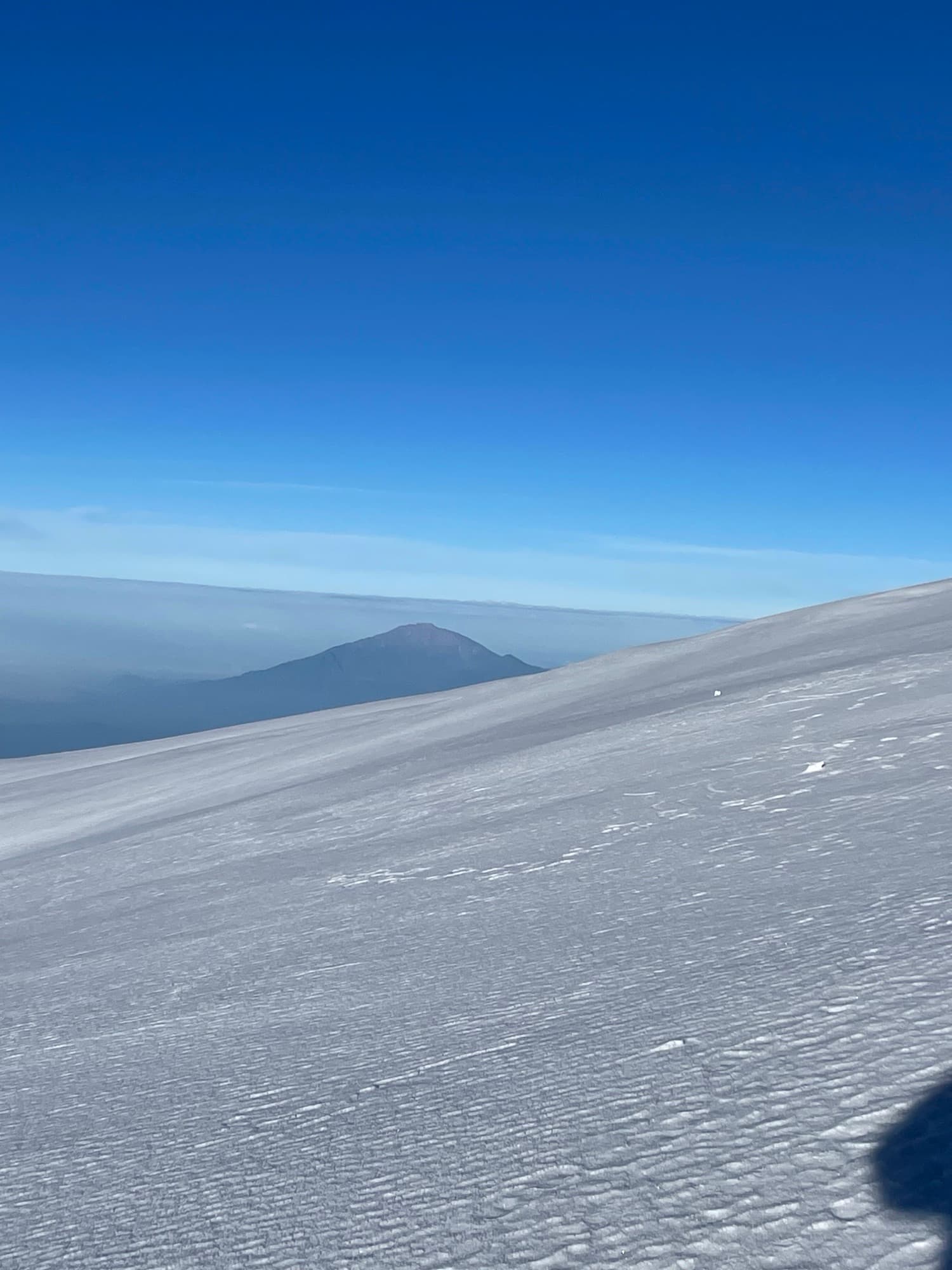 Mount Meru floating above the cloud sea, seen across Kilimanjaro's summit snowfield