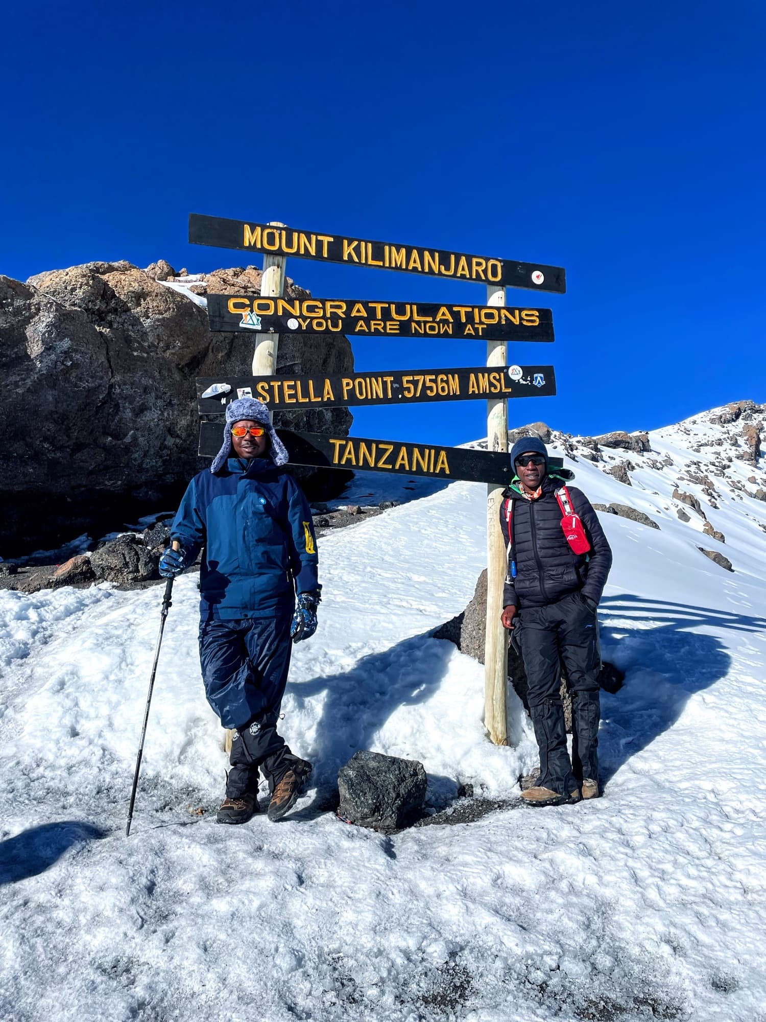 Two guides at the Stella Point sign, 5,756 m, on the crater rim