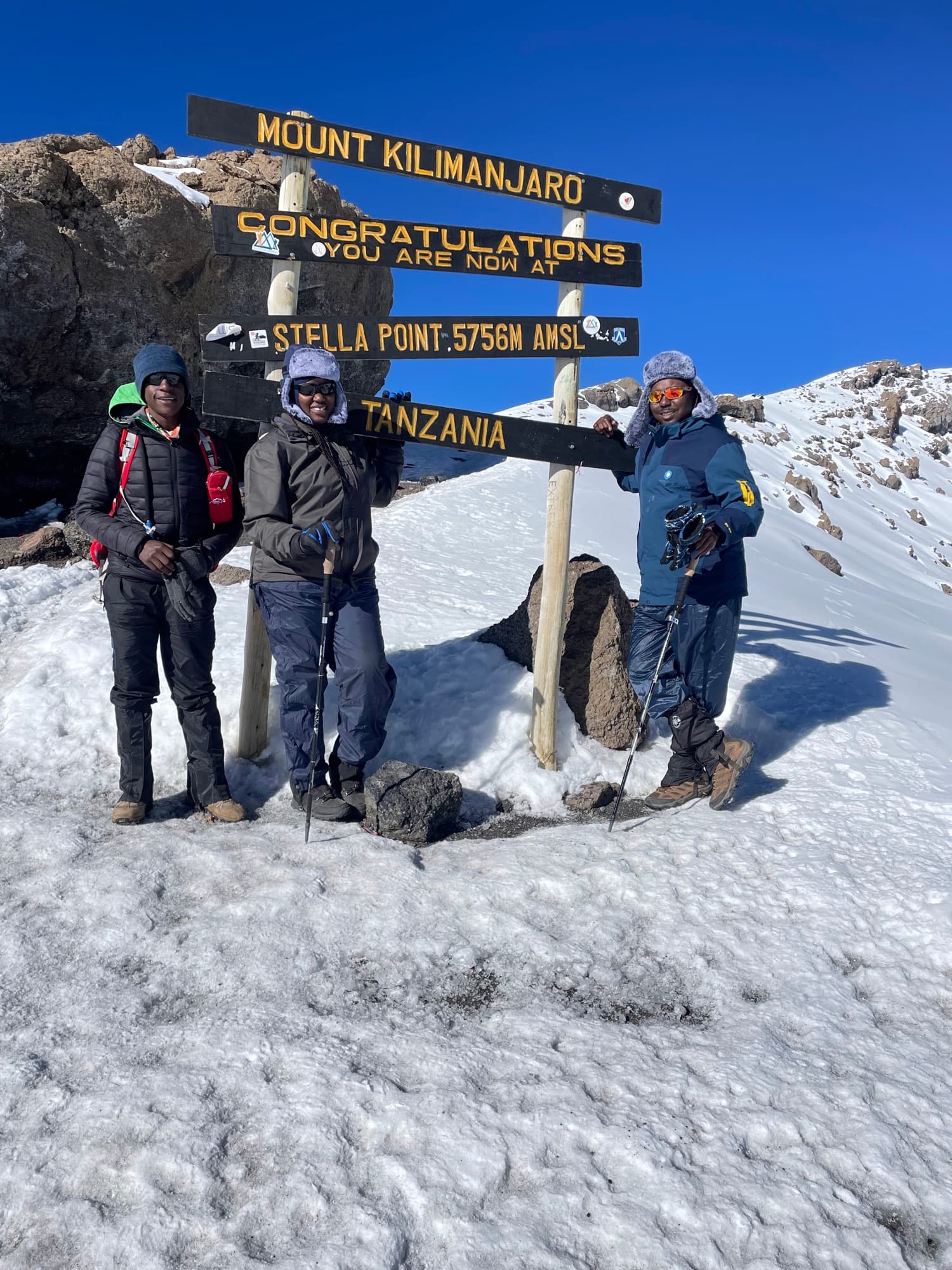 Three team members posing at the Stella Point sign after summit night