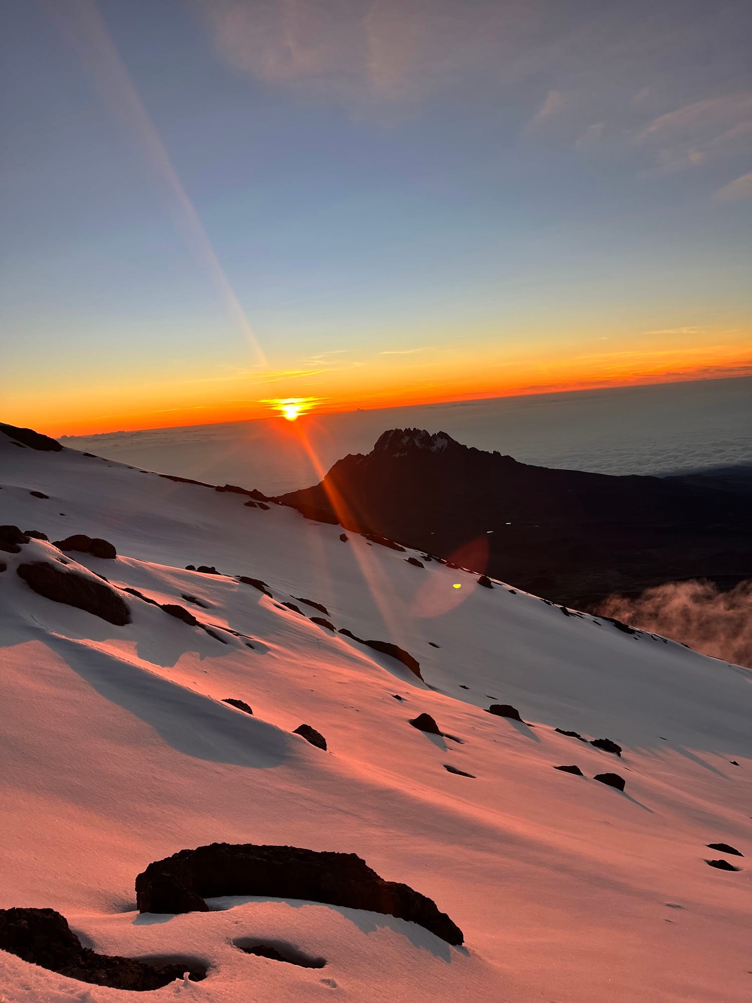 Sunrise breaking over Mawenzi from the snow-covered summit slopes of Kilimanjaro