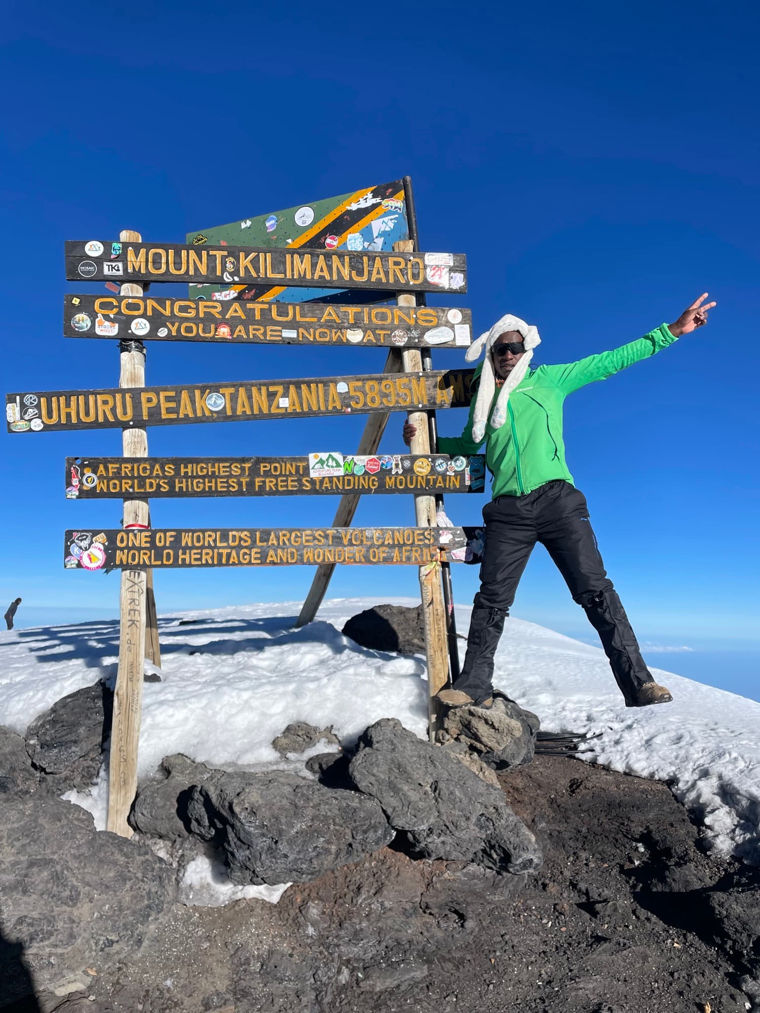 A guide celebrating at the Uhuru Peak sign, 5,895 m, Africa's highest point